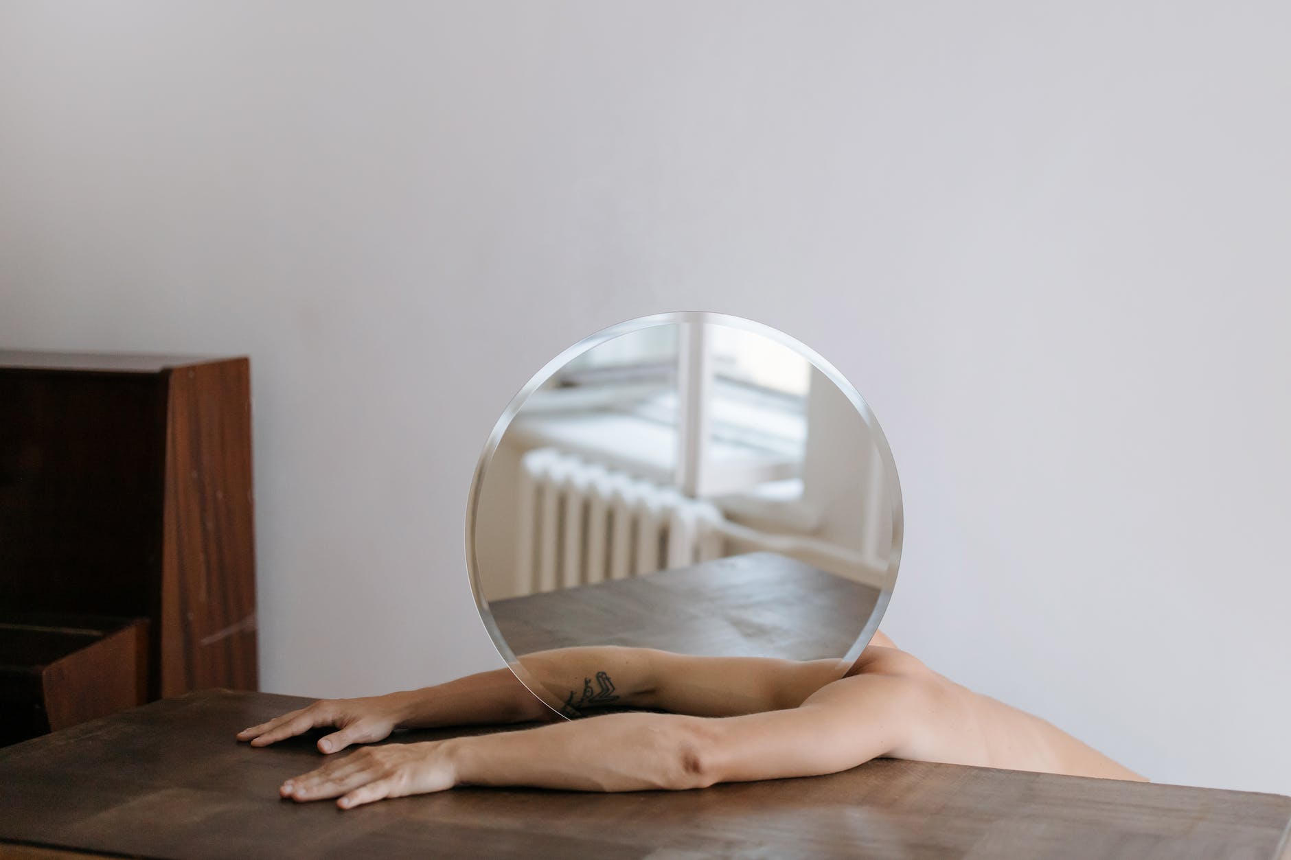 person holding round mirror on brown wooden table